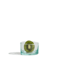 Small hand-blown recycled glass tumbler with a kiwi slice inside, isolated on a deep green ground