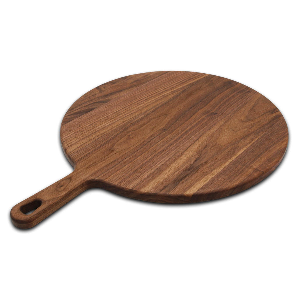 Round walnut pizza paddle lying at an angle on white with the handle pointing left
