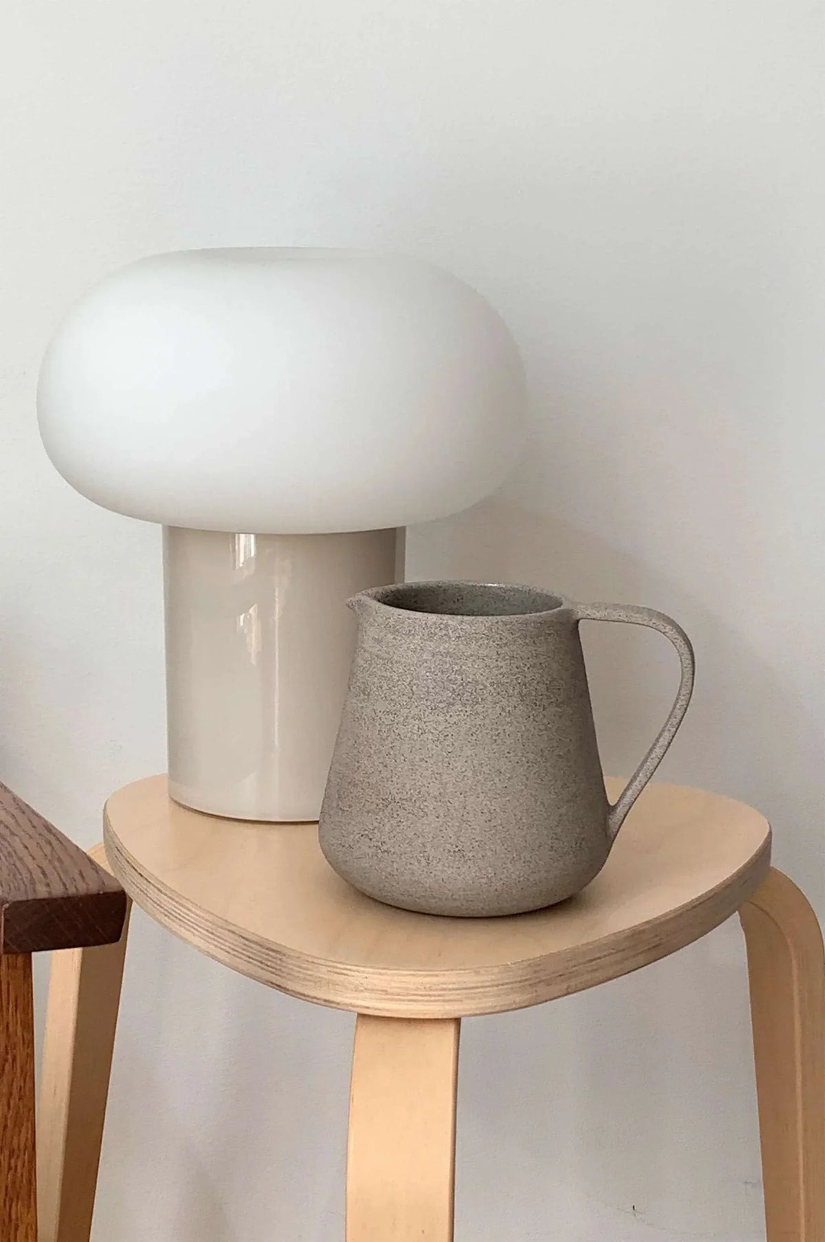 Concrete-Toned Stoneware Pitcher shown in warm window light on an adobe toned shelf at home