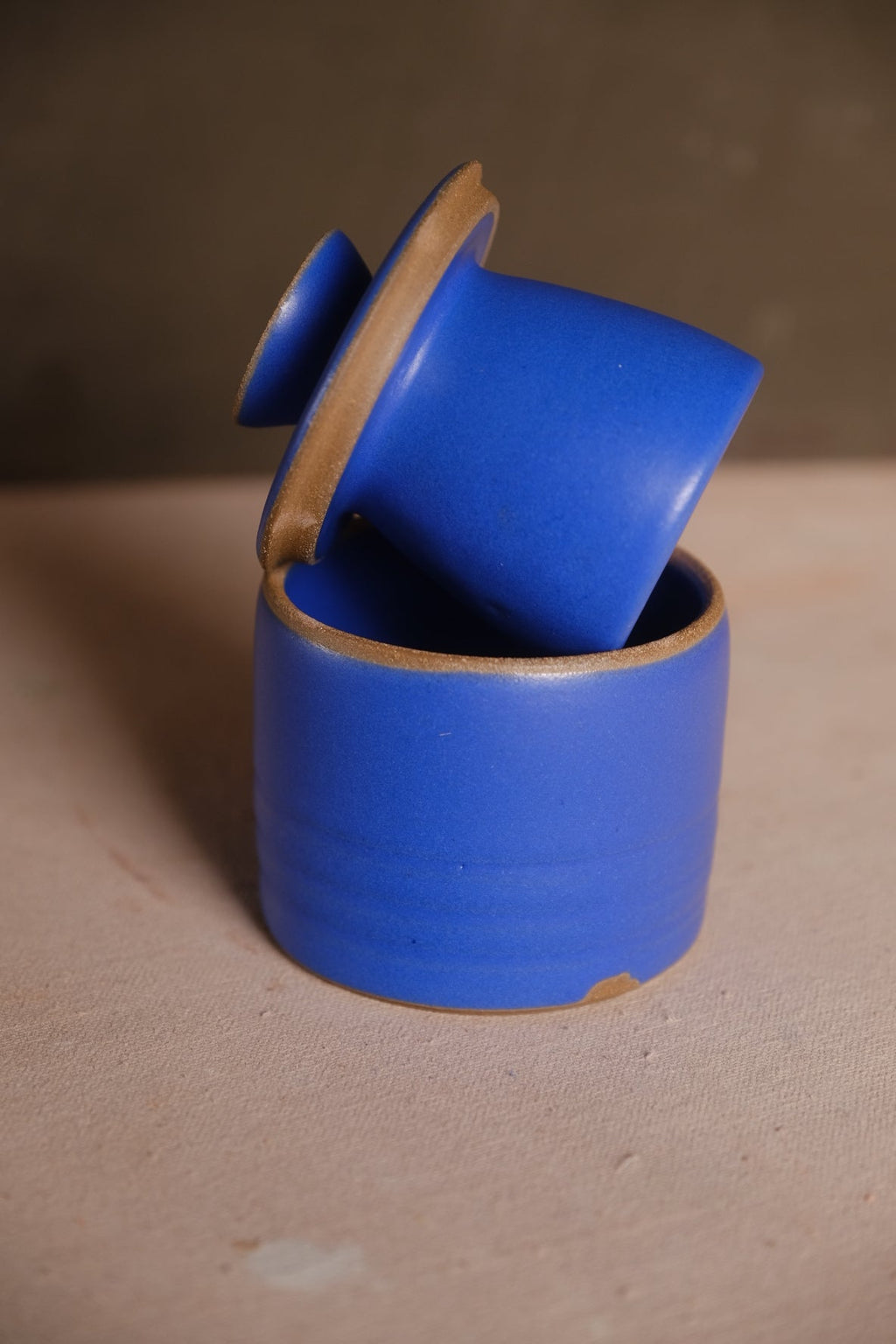 Stoneware French butter keeper in a matte cobalt blue glaze with the bell lid angled out of the crock