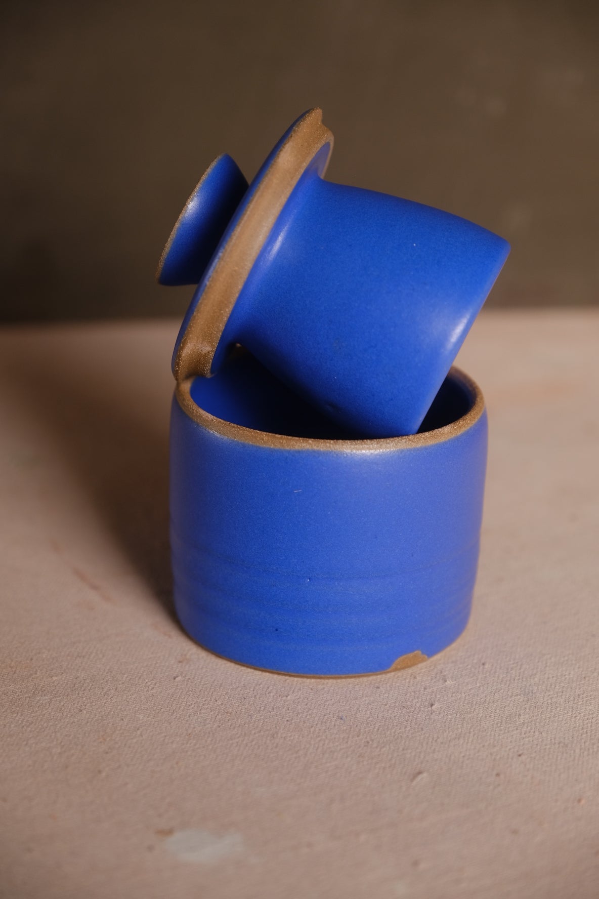 Stoneware French butter keeper in a matte cobalt blue glaze with the bell lid angled out of the crock