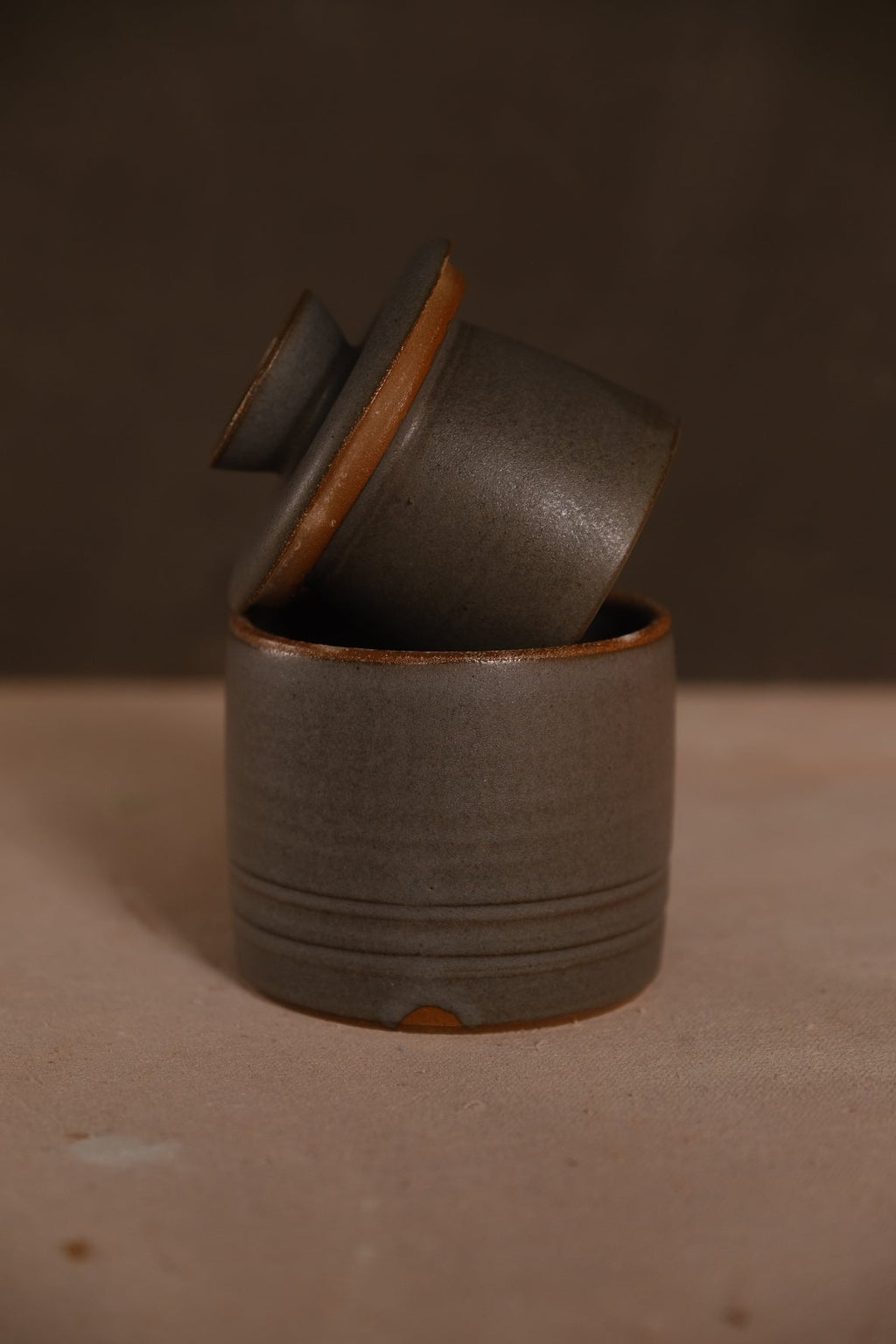 Stoneware French butter keeper in a matte charcoal gray glaze with incised rings, lid propped in the base