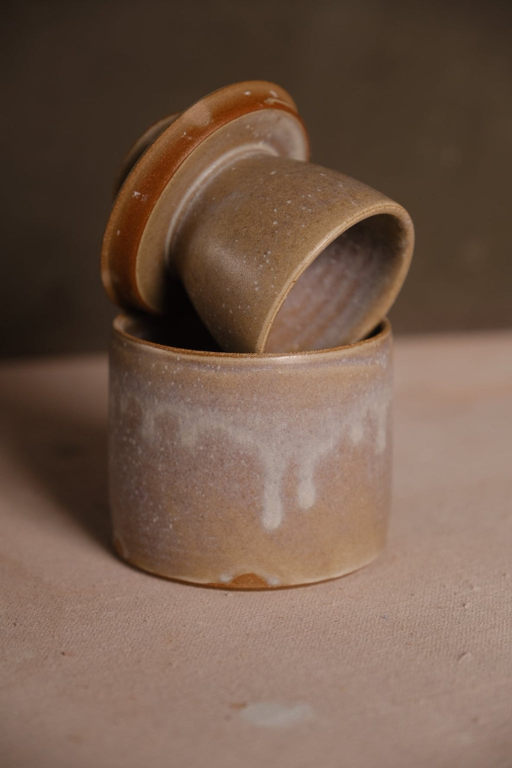 Stoneware French butter keeper in an ochre glaze with pale drips, bell lid turned to show the hollow cup