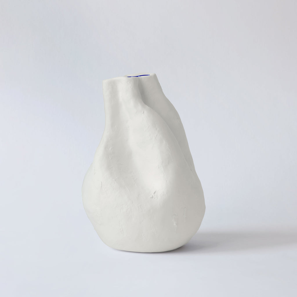Pear-shaped white sculpted porcelain vase seen in profile against a soft grey studio backdrop