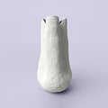 Extra tall slender white sculpted porcelain vase with a notched rim against a soft lavender backdrop