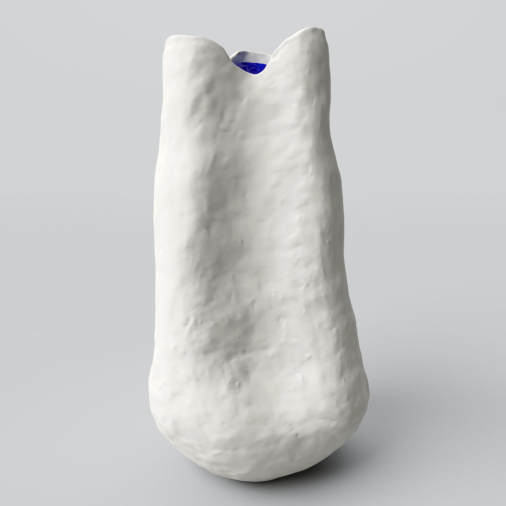 Extra tall white porcelain vase with a narrow neck and a hint of cobalt inside on a pale grey backdrop