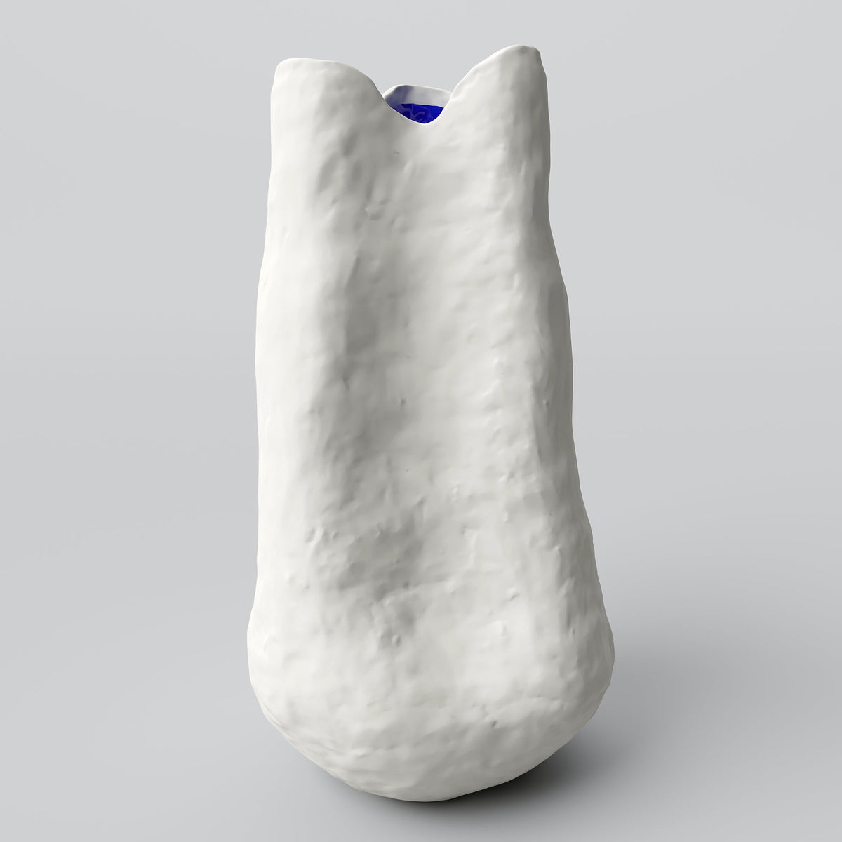 Extra tall white porcelain vase with a narrow neck and a hint of cobalt inside on a pale grey backdrop