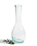Tall clear recycled glass bottle carafe with a slim neck shown on a deep green background