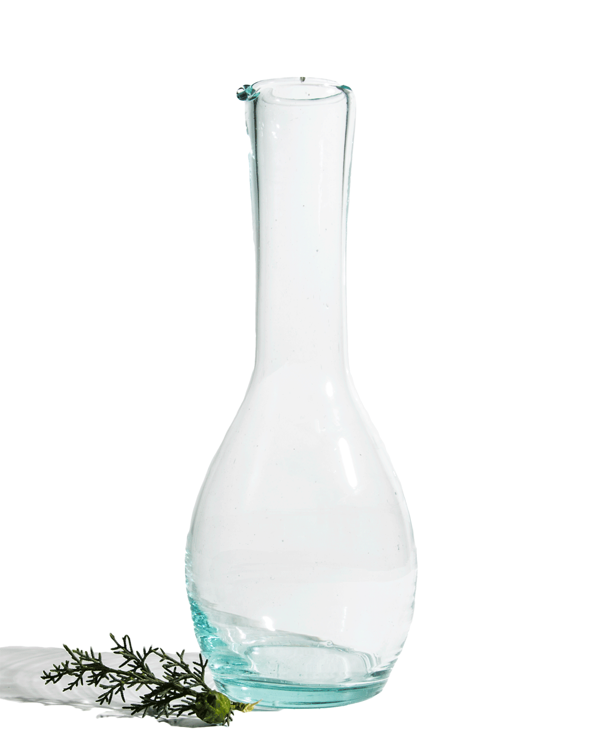 Tall clear recycled glass bottle carafe with a slim neck shown on a deep green background