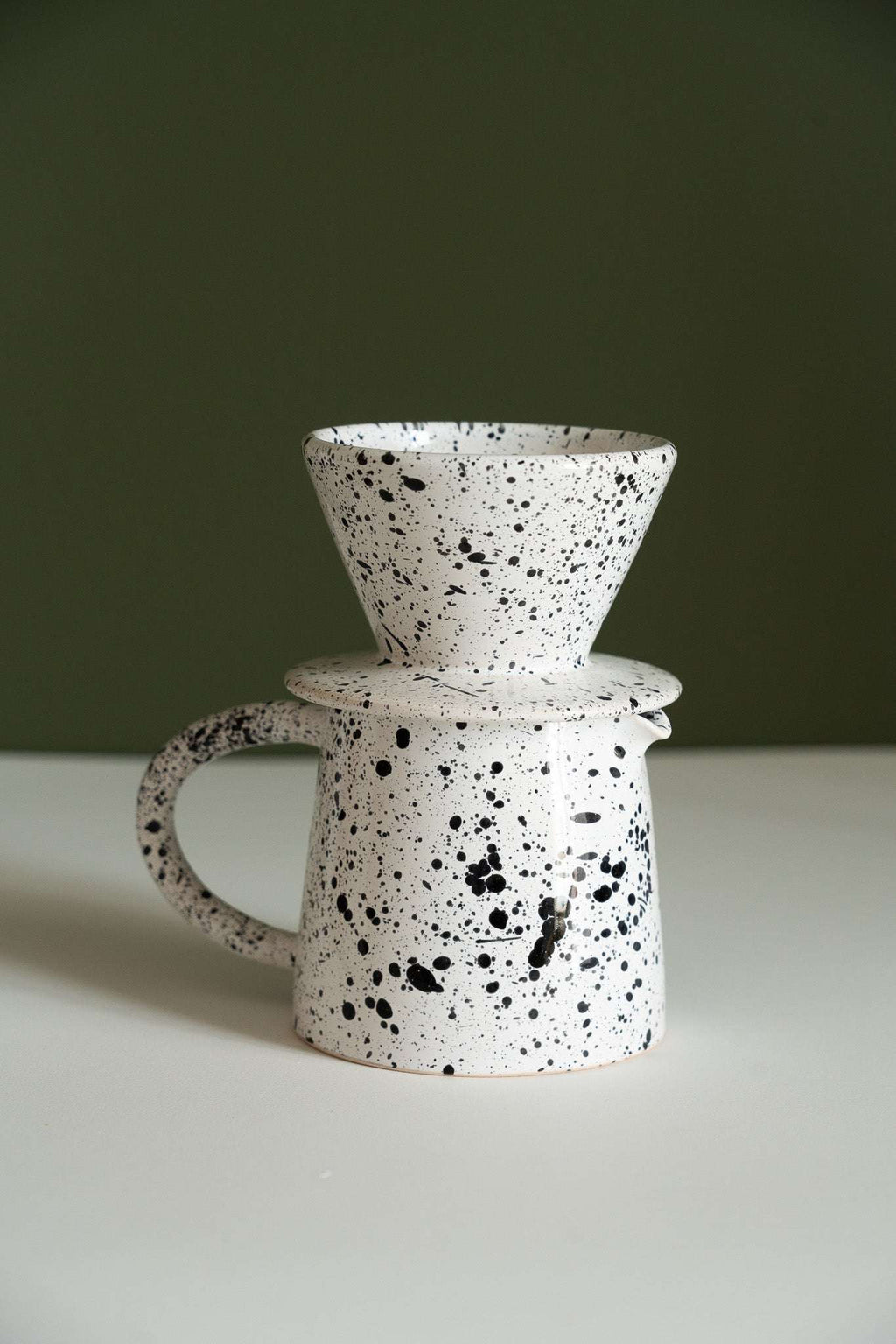Fine speckle pour-over set with the cone dripper balanced on top of the stoneware pitcher