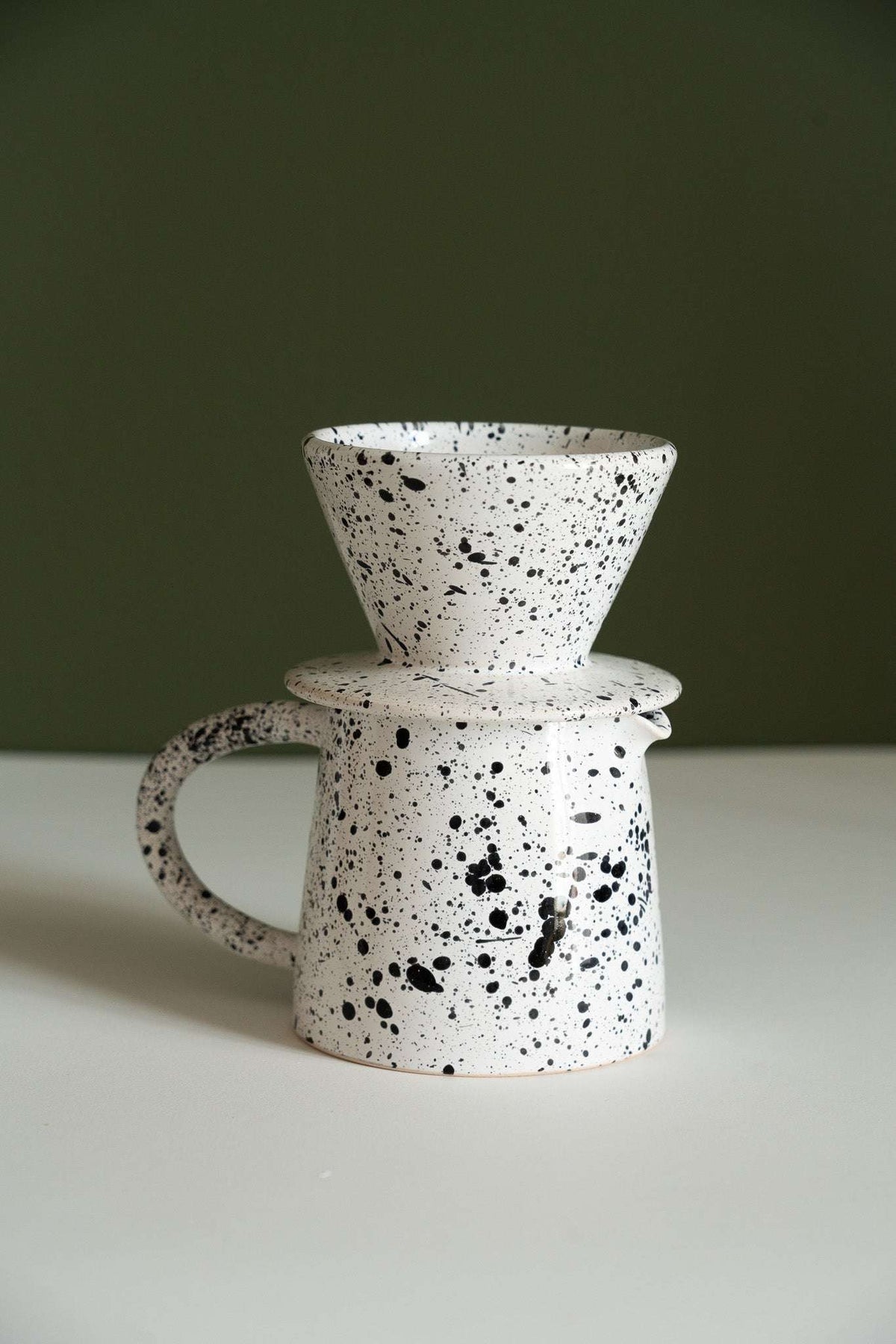 Fine speckle pour-over set with the cone dripper balanced on top of the stoneware pitcher