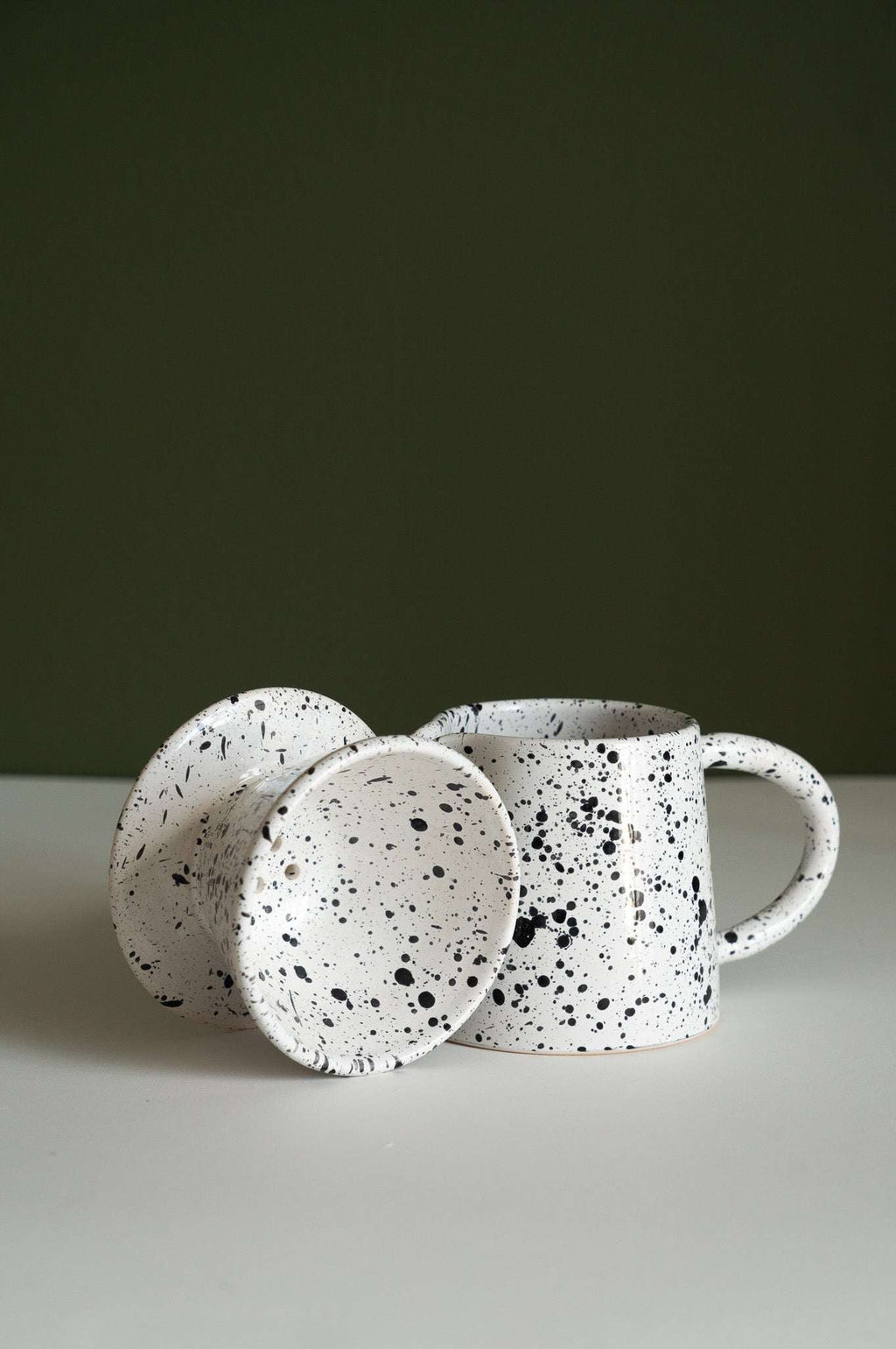 Fine black speckle dripper and pitcher arranged together on a white surface in soft light