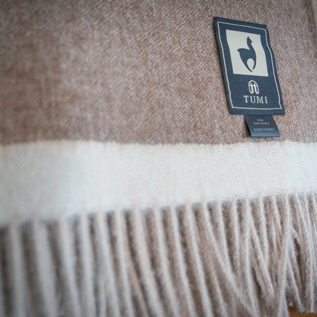 Macro view of the cream band and natural fringe on a brown baby alpaca herringbone throw
