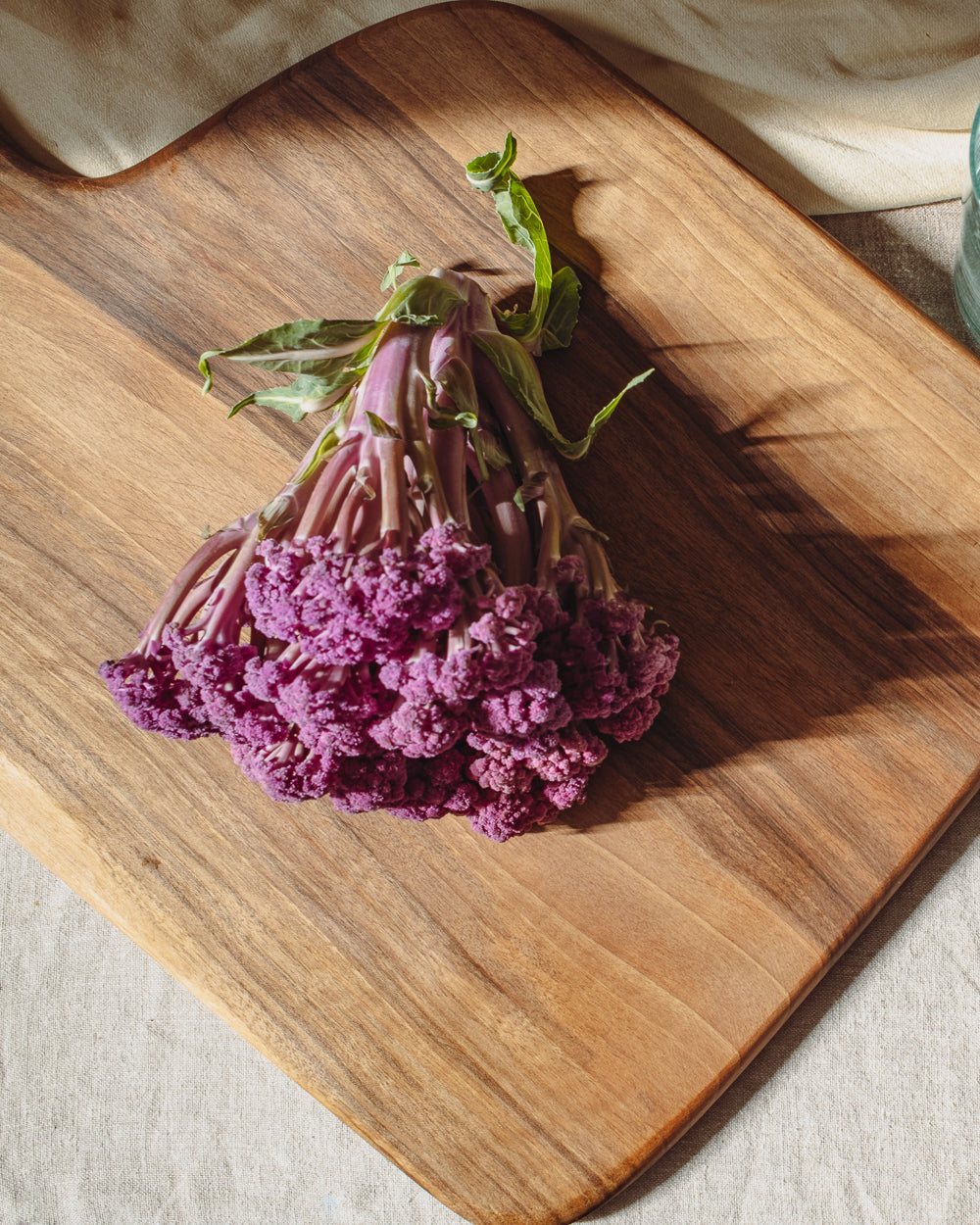 Close view of a large walnut board with a bundle of purple amaranth resting across its oiled grain