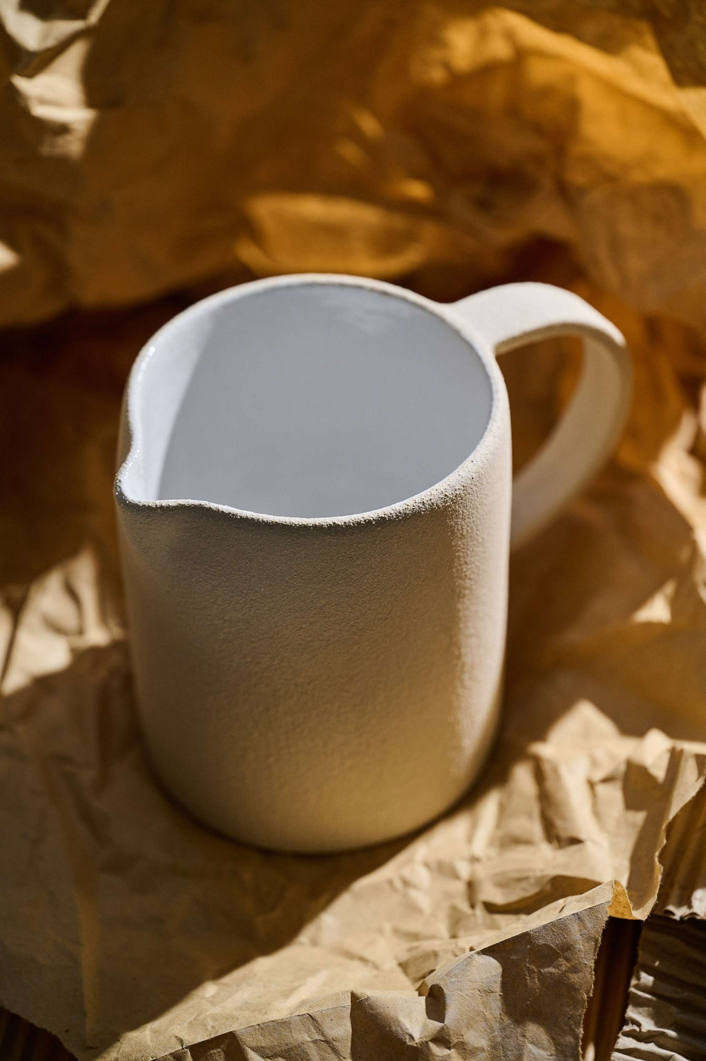 Close view of the stoneware pitcher showing its glossy white inside and the matte unglazed clay outside