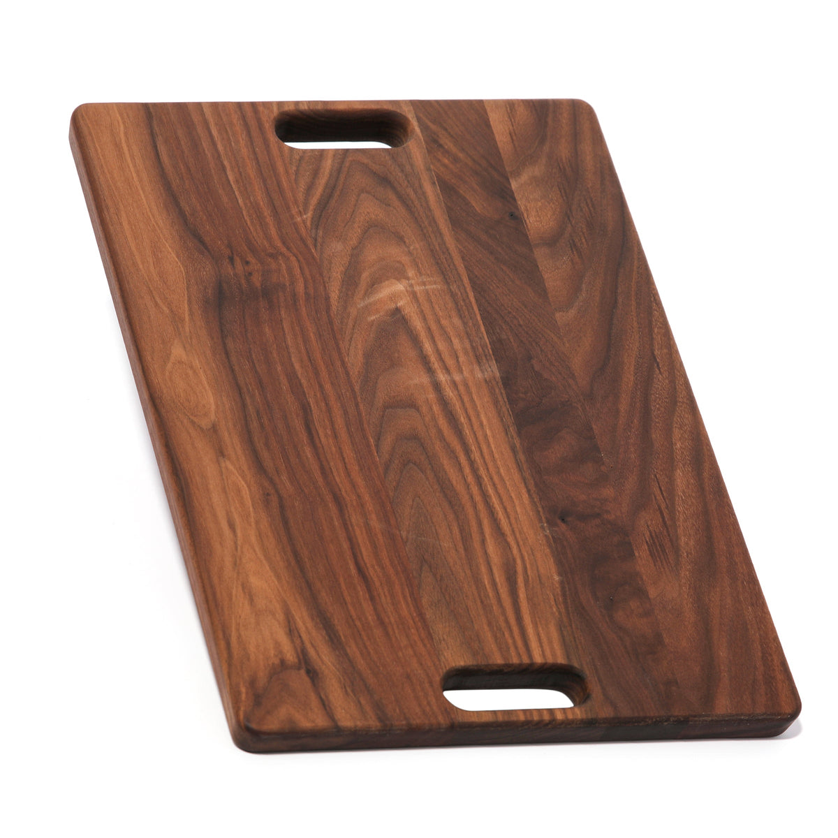 Walnut cutting board with cutout handles at both ends, 18 x 12 in, lying at an angle on white