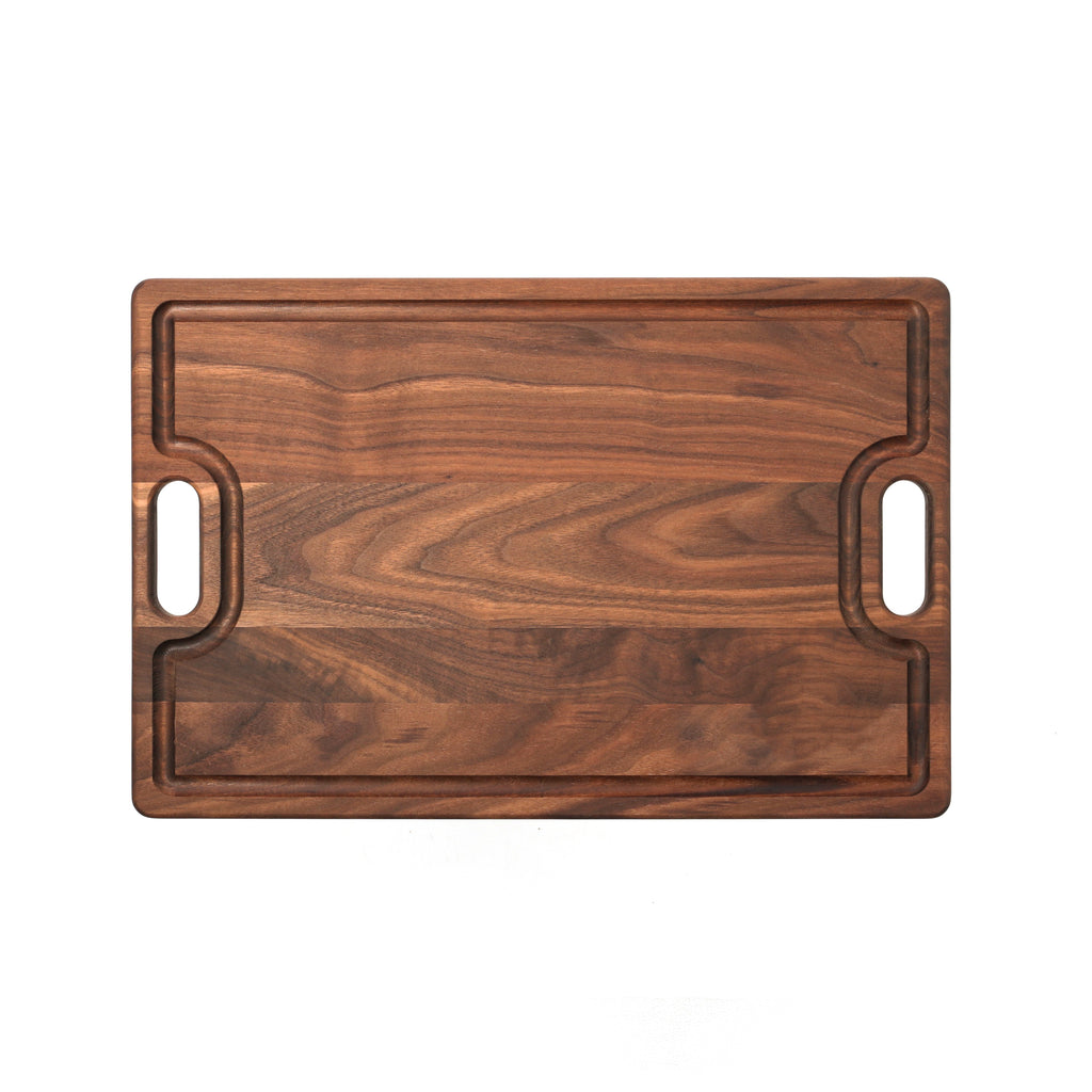 Walnut cutting board with cutout handles and a juice groove, 18 x 12 in, straight overhead view on white