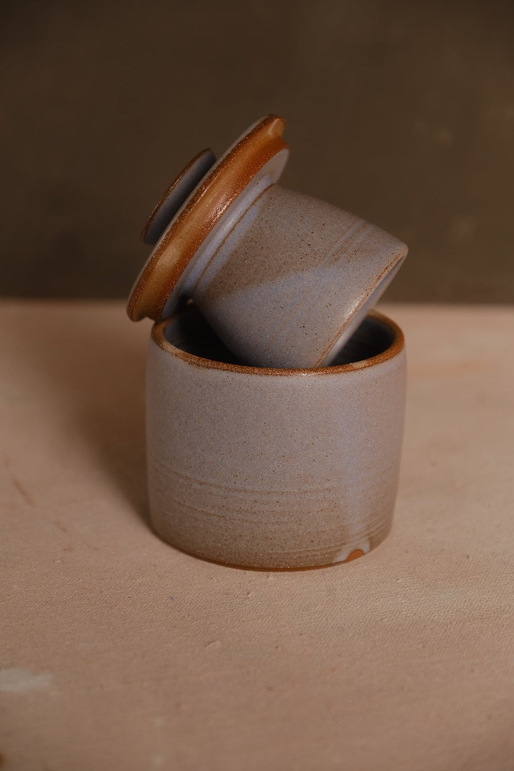 Stoneware French butter keeper in a soft periwinkle gray glaze with a toasted clay rim, lid set at an angle
