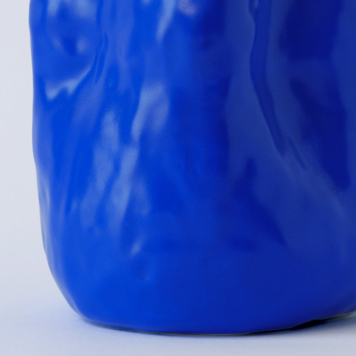 Sculpted Cobalt Blue Porcelain Vase shown in warm window light on an adobe toned shelf at home