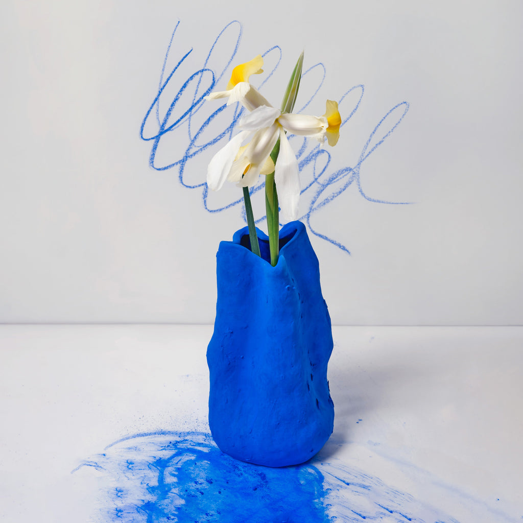 Sculpted Matte Blue Porcelain Vase shown in warm window light on an adobe toned shelf at home