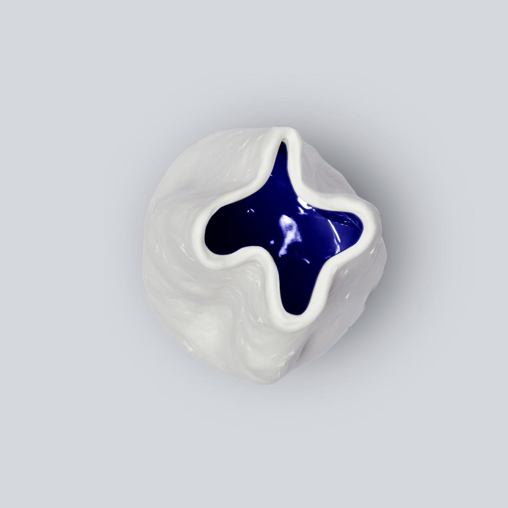 Top-down view into a tall white porcelain vase showing its four-point rim and glossy cobalt interior