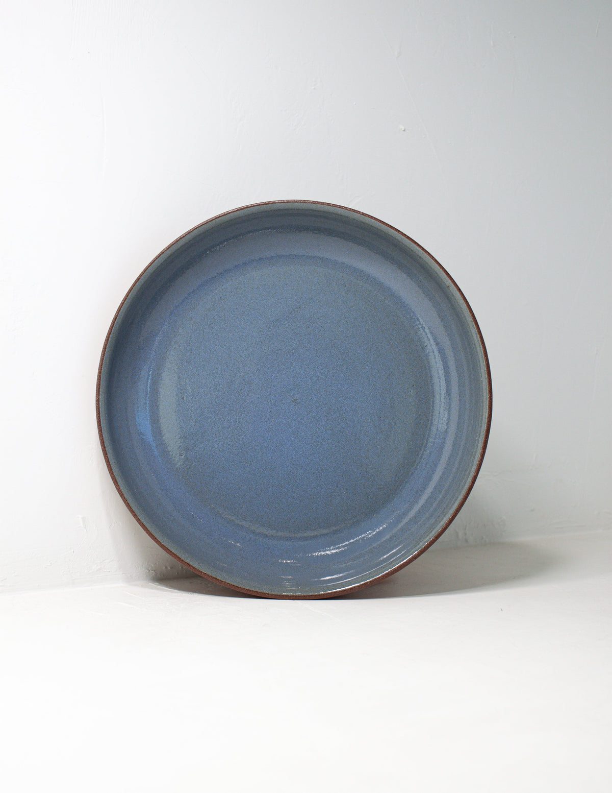 Dusty blue glazed coupe serving bowl standing upright to show the full glazed interior