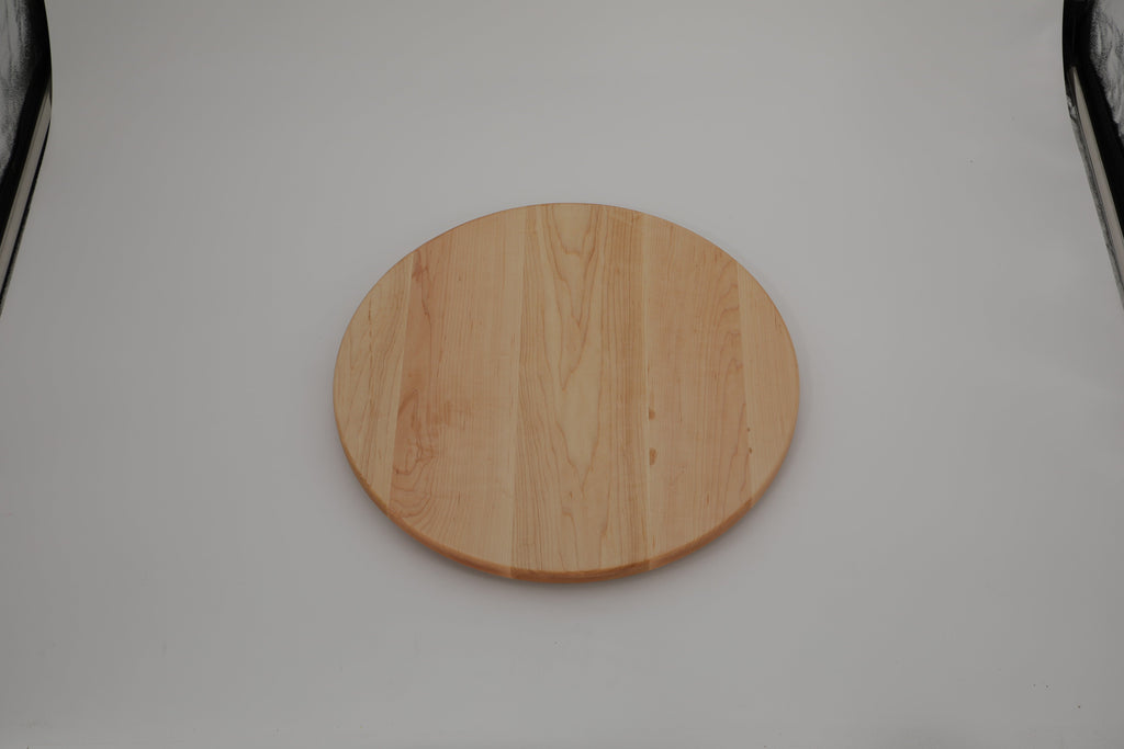 Round maple cutting board photographed flat on a grey studio surface, seen from above at a distance
