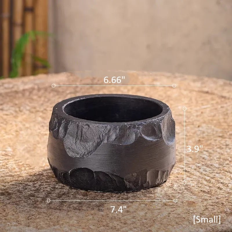 Small black cement planter, 6.66 in across the top and 3.9 in tall, on a round stone table