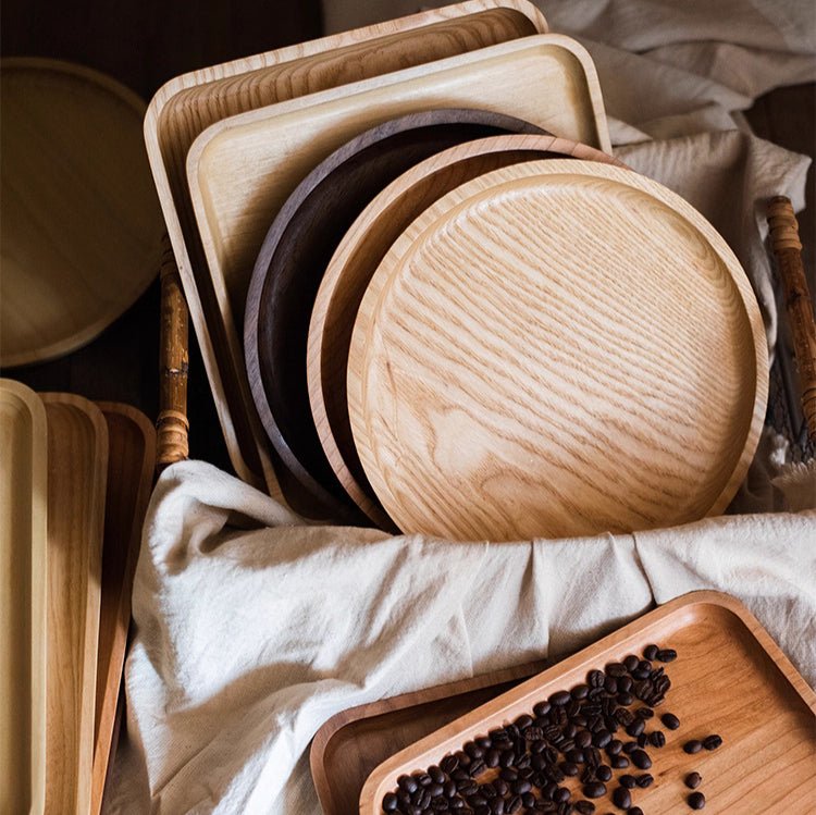 Solid wood serving trays in ash, cherry and walnut, round and rectangle, stacked in a basket with linen and coffee beans