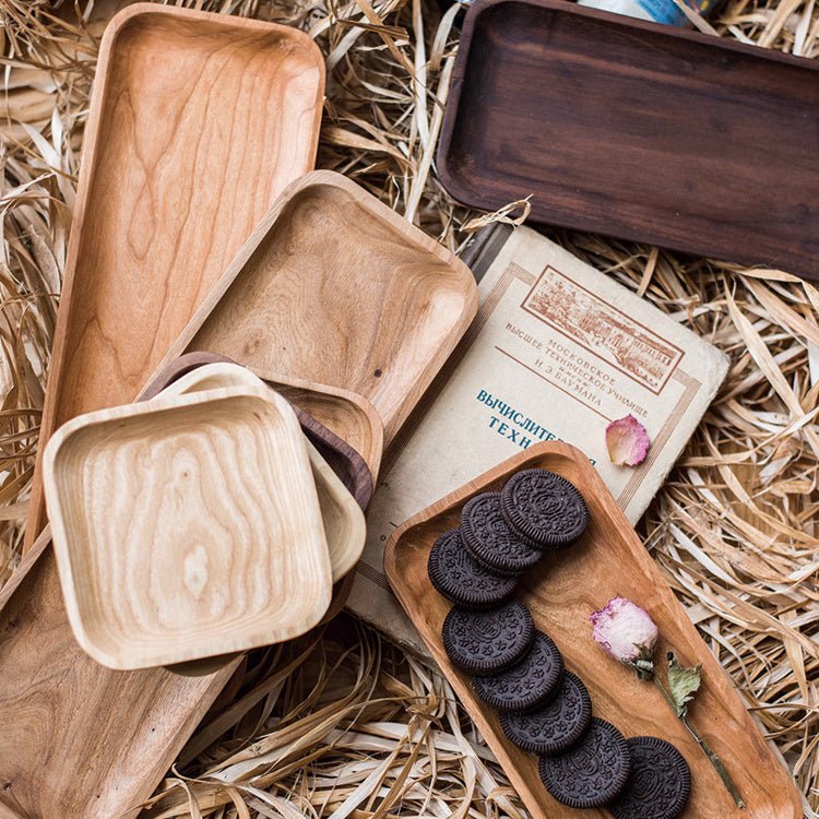 Solid wood snack plates in ash, cherry and walnut, square and long, with cookies and a dried rose on straw