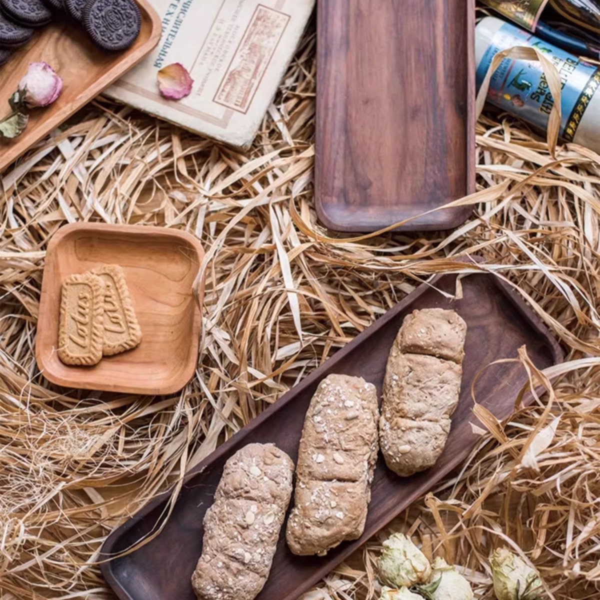 Long walnut snack plate with three bread rolls and a small ash square with biscuits on dried straw