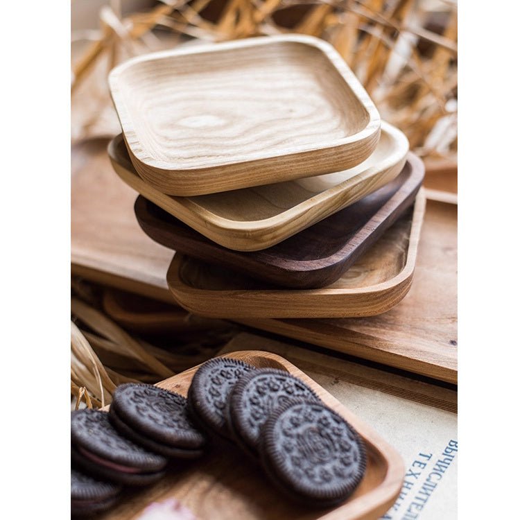 Stack of small square snack plates in ash, cherry and walnut beside a cherry plate of cookies