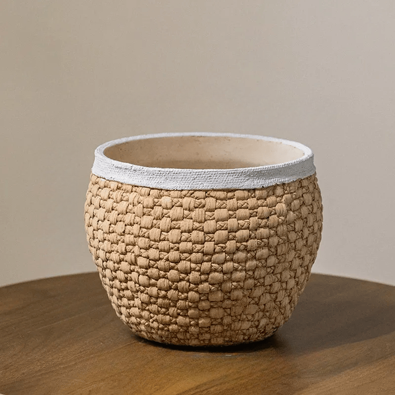 Medium woven texture cement planter in warm tan with an ivory rim on a wooden tabletop