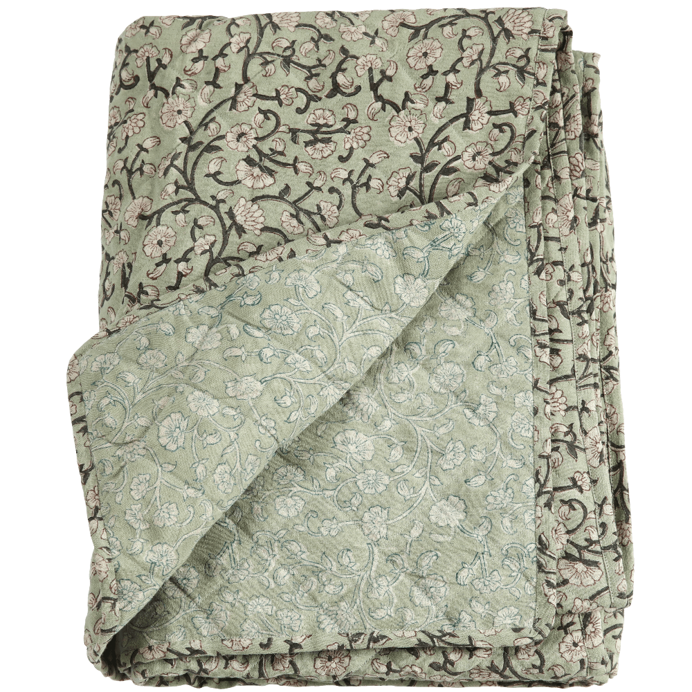 Folded quilted linen coverlet in sage green block print with dark vines, corner turned back to show the paler reverse