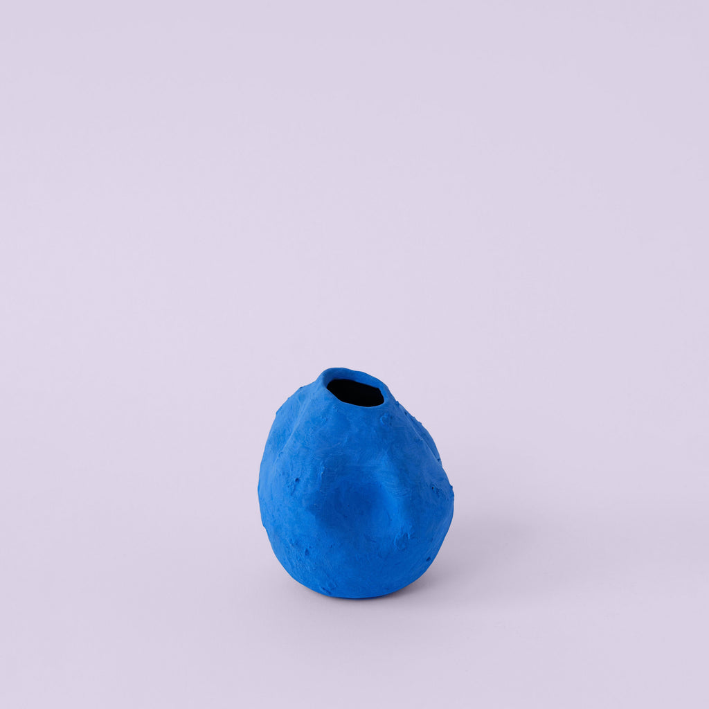 Matte Blue Porcelain Bud Vase photographed on a bone white surface in soft natural light