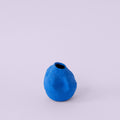 Matte Blue Porcelain Bud Vase photographed on a bone white surface in soft natural light