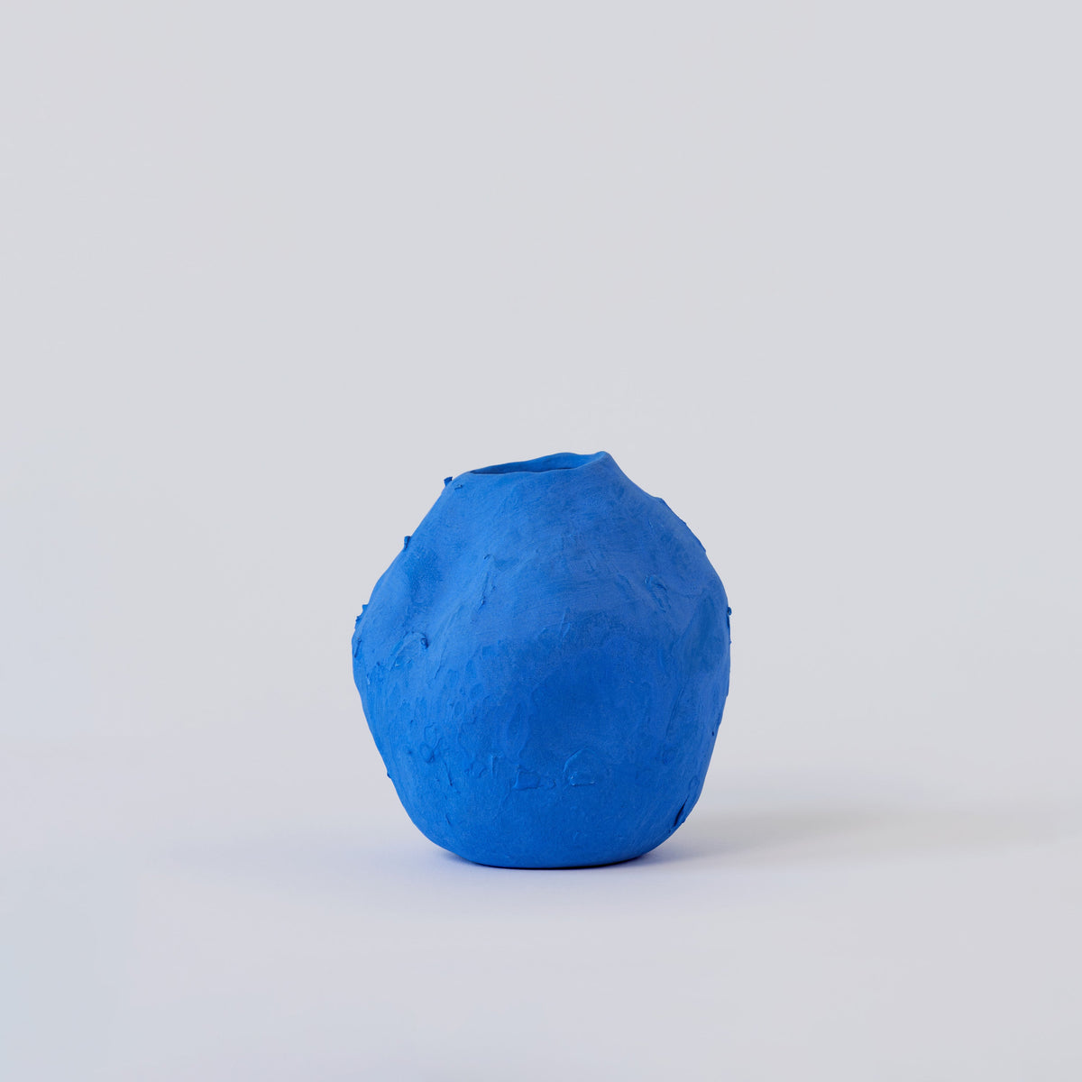 Matte Blue Porcelain Bud Vase shown from a second angle against a pale neutral backdrop