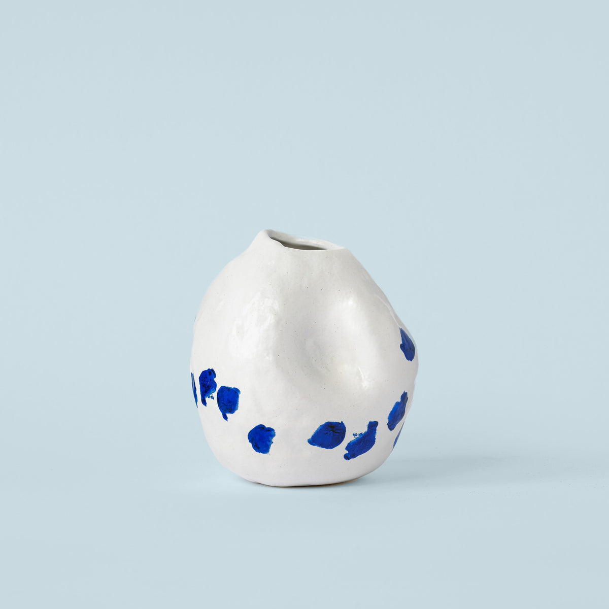White and Blue Porcelain Bud Vase photographed on a bone white surface in soft natural light
