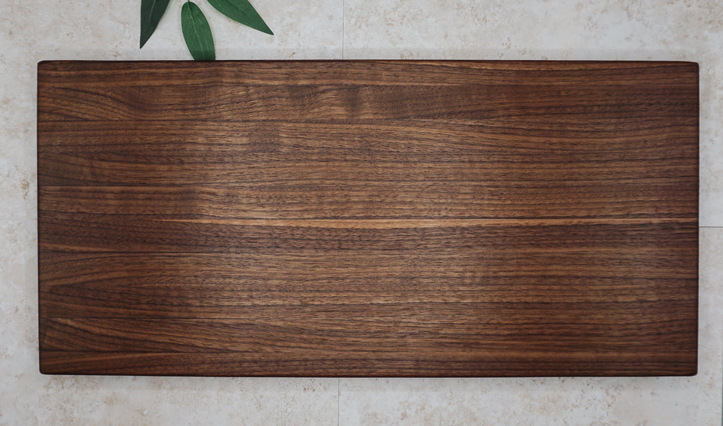 Overhead view of the large walnut board showing light and dark walnut grain on a stone surface