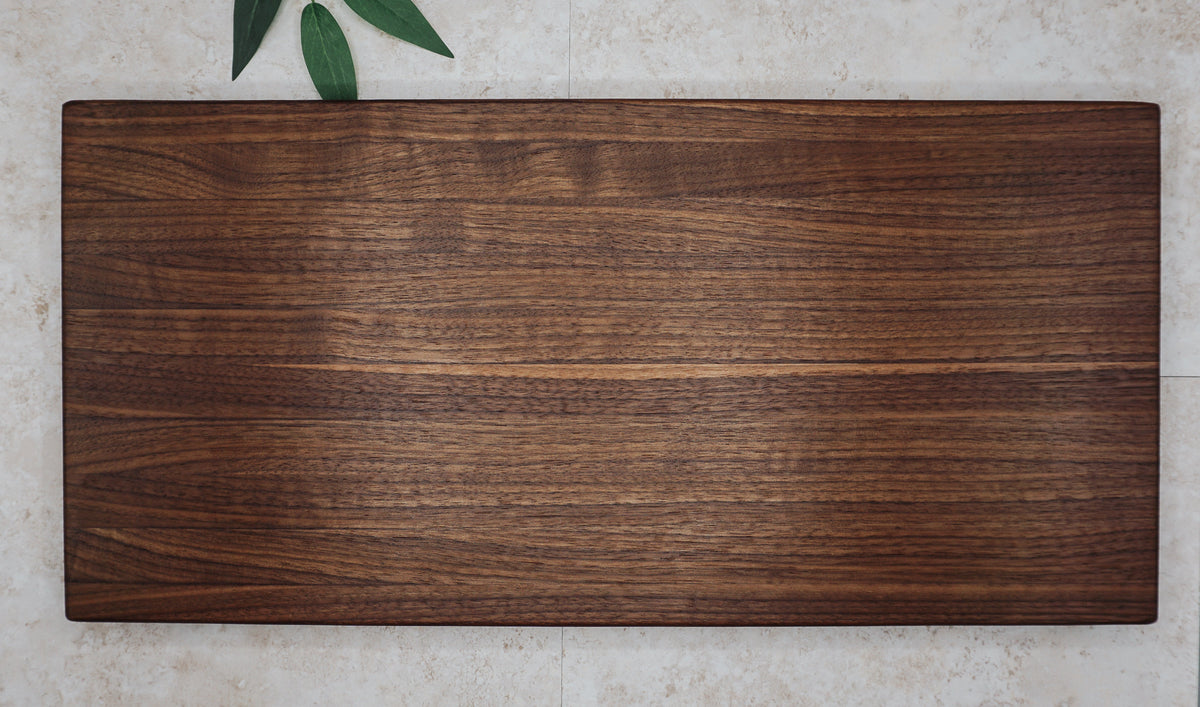 Overhead view of the large walnut board showing light and dark walnut grain on a stone surface