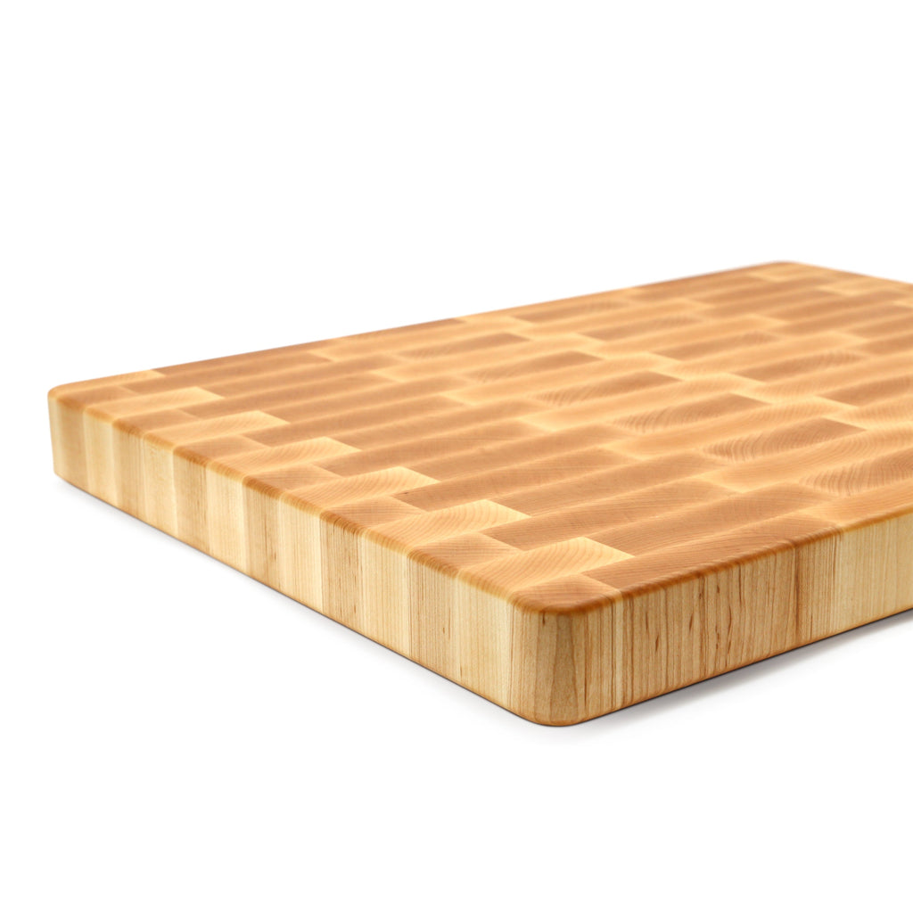 Close view of the layered edge of an end grain maple cutting board, 18 x 12 in, on white