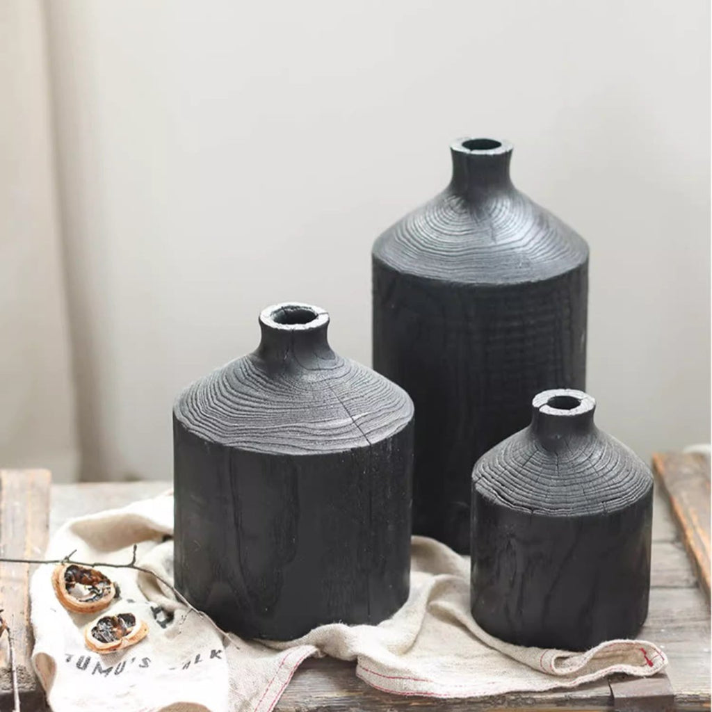 Black wood bottle vases in small, medium and large on a linen cloth, showing growth rings on the shoulder
