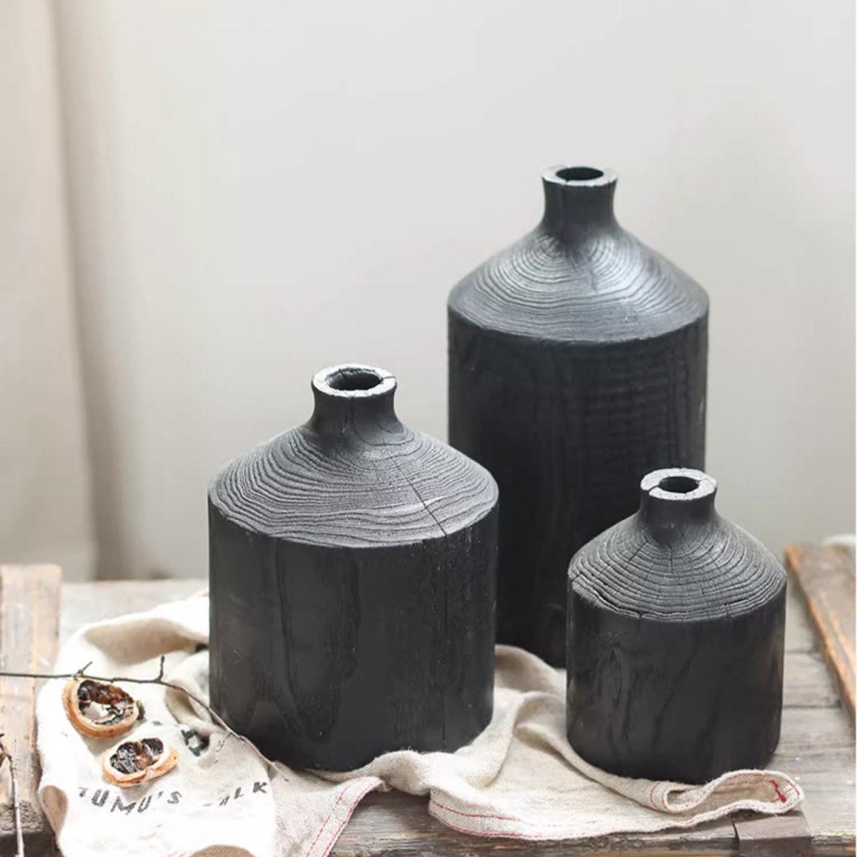 Black wood bottle vases in small, medium and large on a linen cloth, showing growth rings on the shoulder