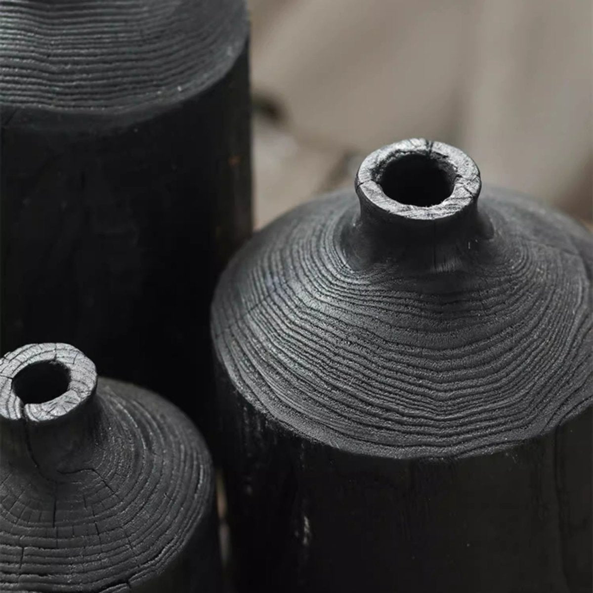 Close view of black wood bottle vase shoulders and narrow openings, showing the ring pattern