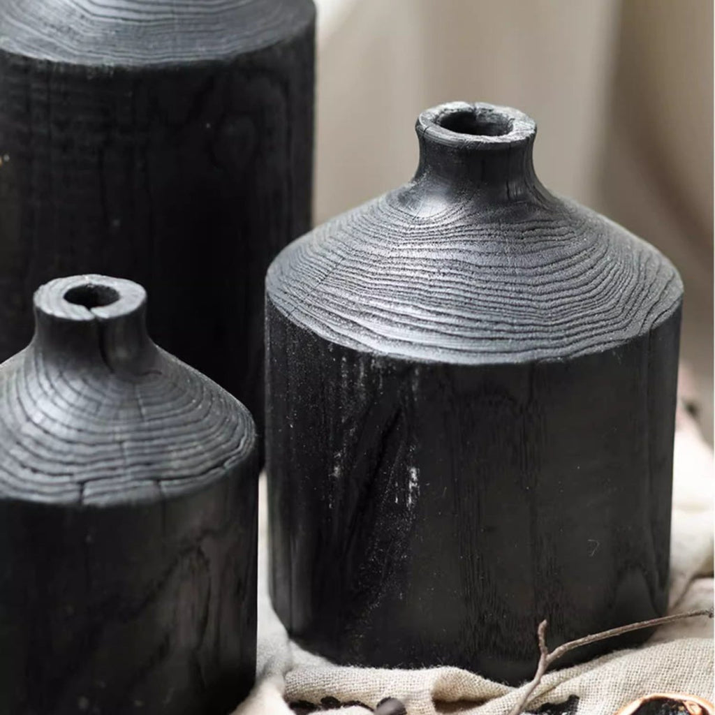 Medium and small black wood bottle vases close up, the finish catching light on the ringed shoulder