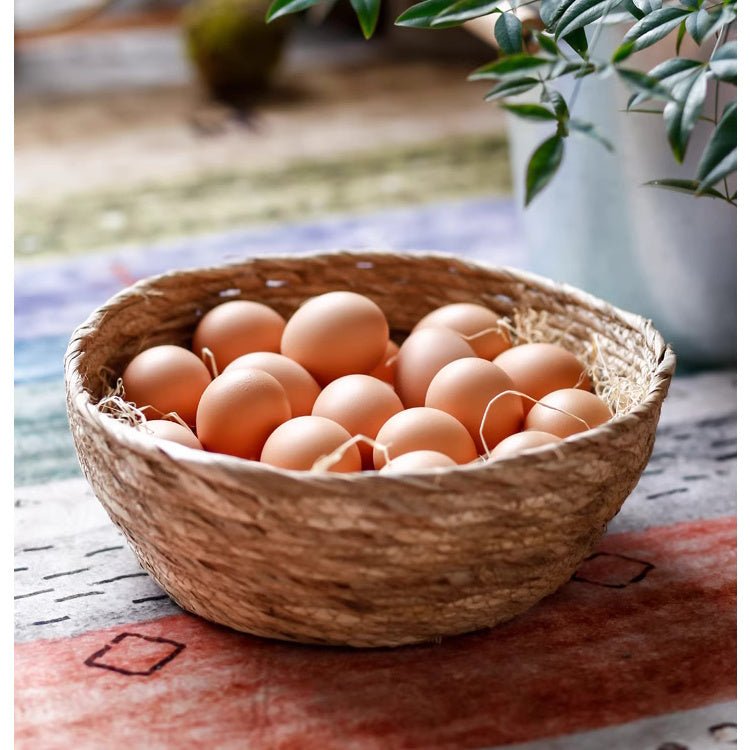 Small round seagrass bowl basket of brown eggs on a red patterned rug, showing the coiled weave