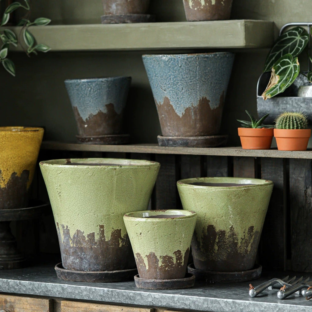 Crackle glaze ceramic planters in slate blue, moss green and mustard yellow on a zinc-topped potting bench