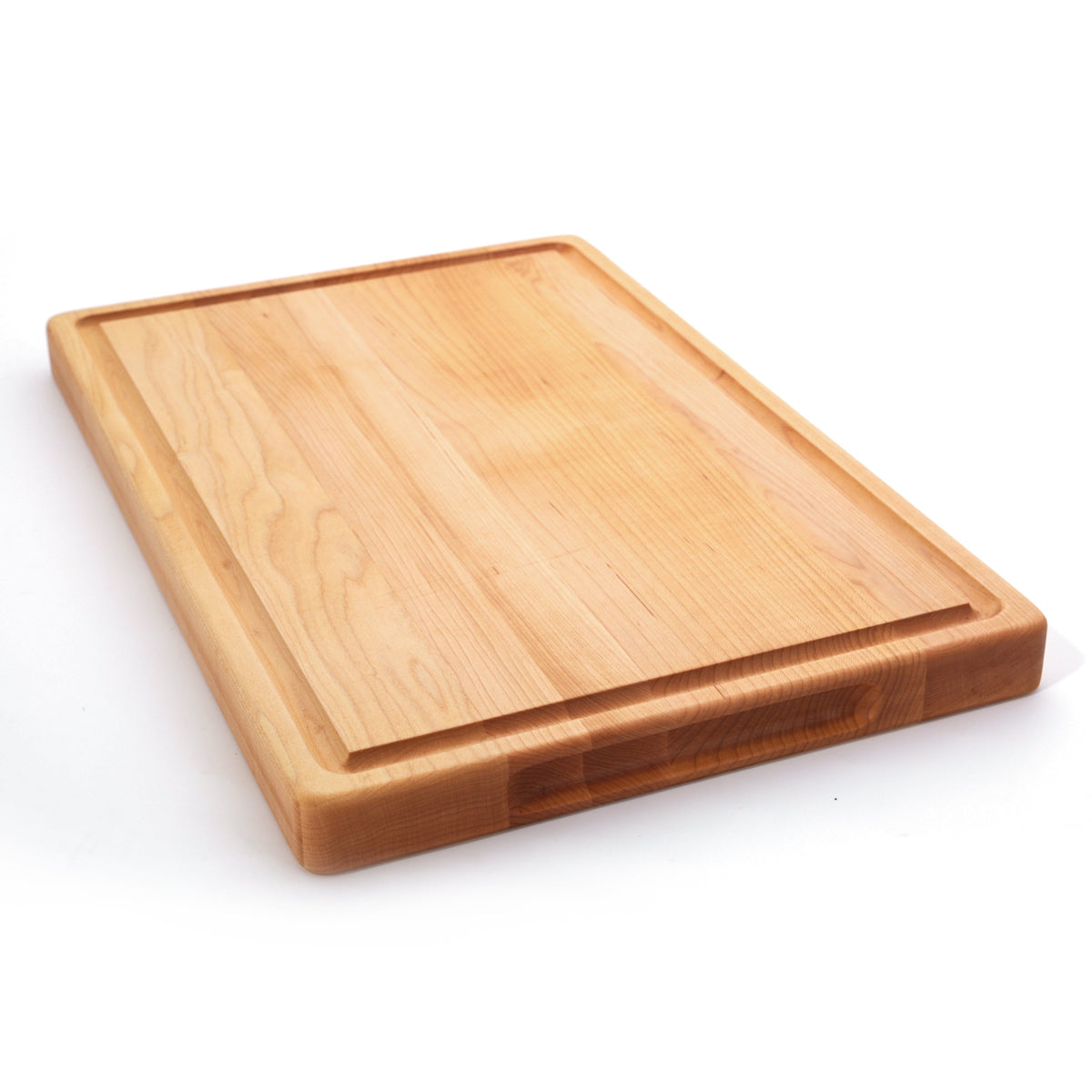 Thick maple cutting board with a juice groove, 20 x 15 in, lying at an angle on white