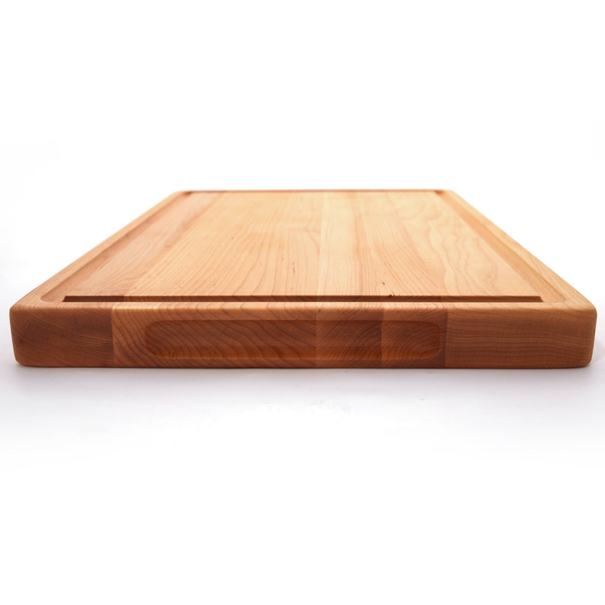 Thick maple cutting board with a juice groove, 20 x 15 in, low side view showing the 1.25 inch edge