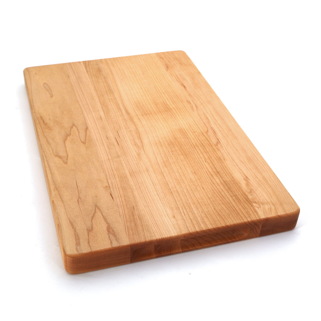 Thick maple cutting board, 20 x 15 in, angled view of the plain face with warm grain on white